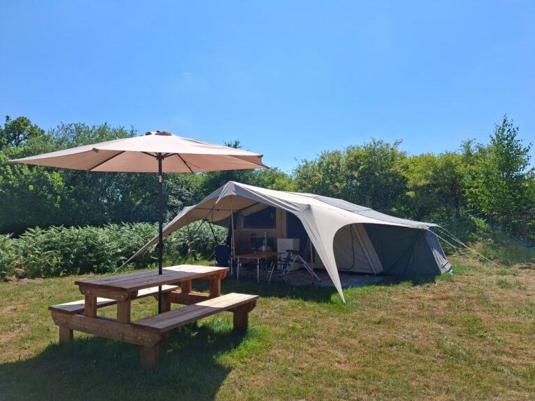 De tenttrailer met een parasol en picknicktafel op het gras